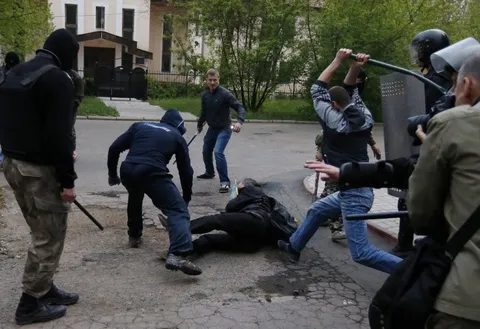 Мужчины с дубинками избивают человека